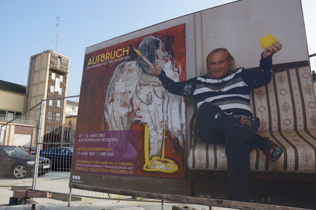Peter Robert Keil beside an Aufbruch exhibition poster, Heidelberg, 2013.